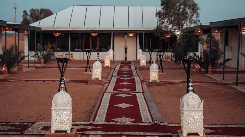 Moonlight luxury Desert Camp outdoor area with white decorative lanterns and red patterned carpet walkway on sandy ground
