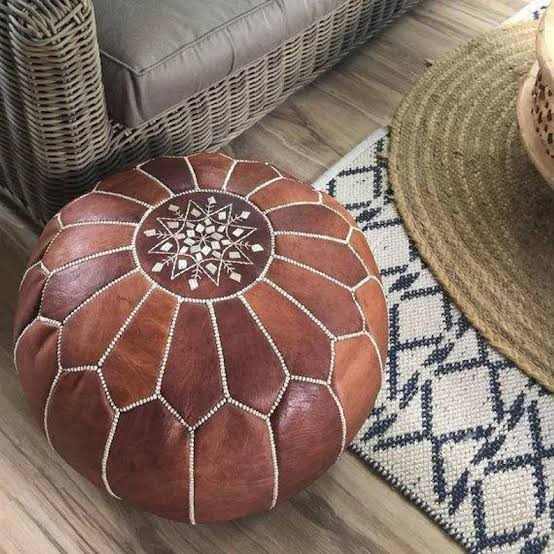 Moroccan pouf in brown leather with intricate white stitched pattern, handmade round ottoman with zip closure detail.