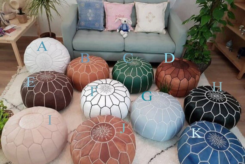 Moroccan pouf collection featuring round leather ottomans in various colors including white, orange, green, brown, black, pink, blue, and beige with stitched geometric patterns