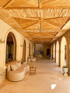 Nasser Palace Suites & Spa corridor with beige stone flooring, arched doorways, ornate wooden ceiling, curved beige seating, and small tables