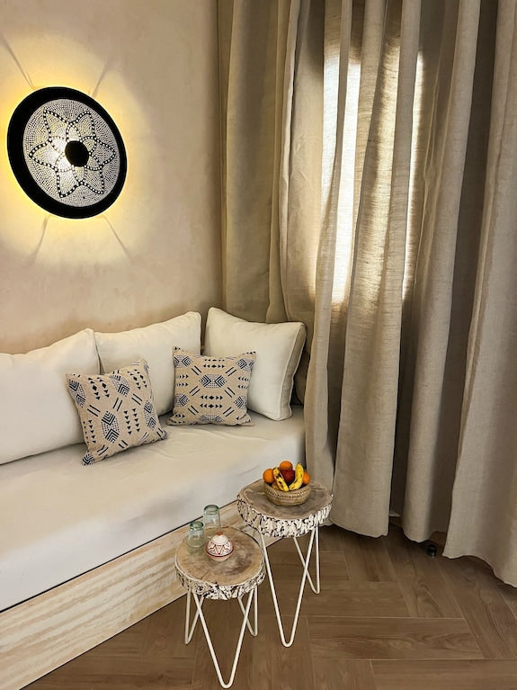 Nasser Palace Suites & Spa cozy seating area with beige curtains, white cushions, patterned pillows, and wooden side tables