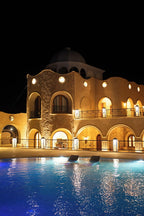 Nasser Palace Suites & Spa illuminated beige Moroccan-style building with arched windows and a blue swimming pool at night