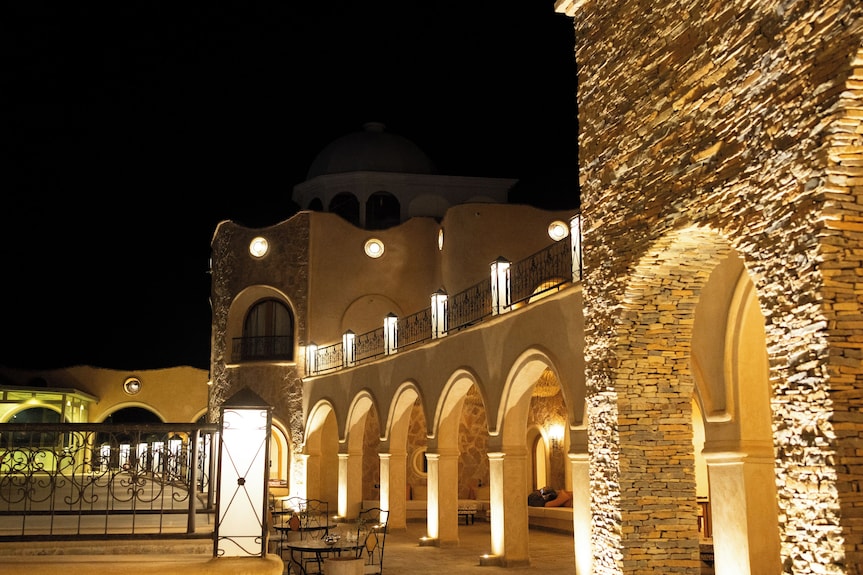 Nasser Palace Suites & Spa illuminated at night featuring warm stone arches and traditional Moroccan architecture under a black sky