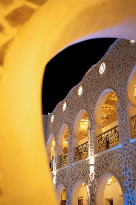 Nasser Palace Suites & Spa stone exterior building with arches and warm yellow lighting at night