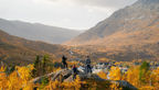 Norway Tromso fjord tour with hikers overlooking an autumn valley village beneath rugged golden mountains