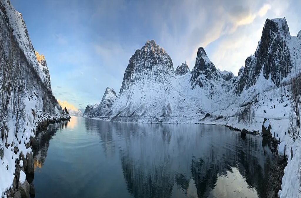 Norway Tromso fjord with snow-covered jagged mountains reflected in calm blue water