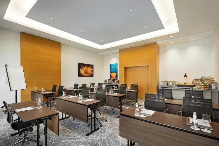 Novotel Makkah Thakher City hotel meeting room with dark wood tables, black chairs, and conference setup
