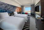 Novotel Makkah Thakher City hotel room with two white beds, colourful cushions, abstract wall art and television