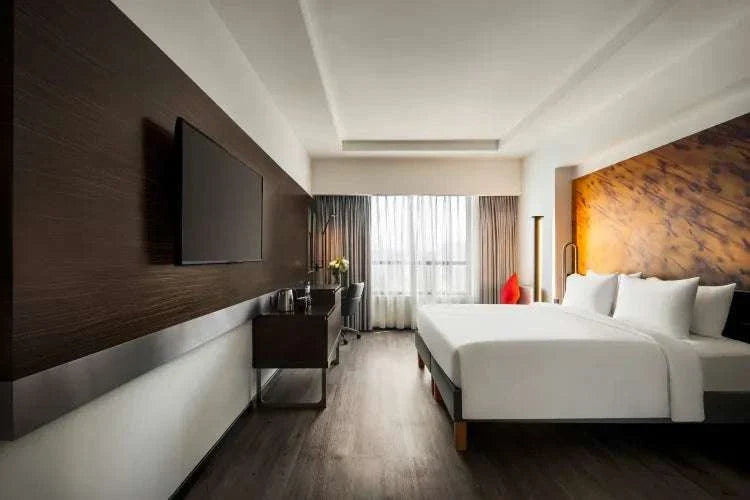 Novotel Makkah Thakher City modern hotel room with two white beds, dark wood panels, and wall-mounted TV