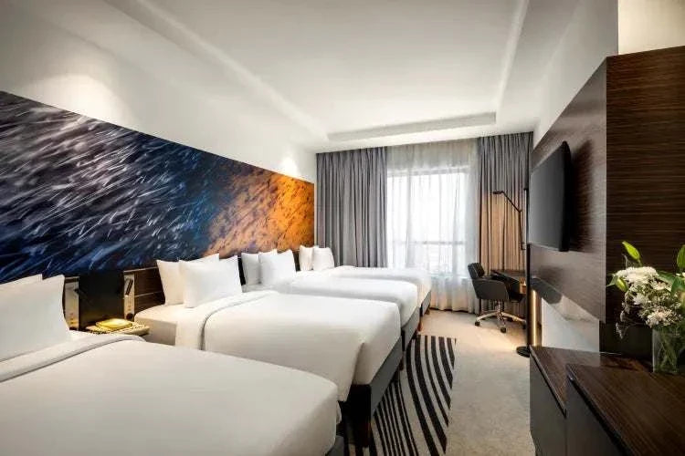 Novotel Makkah Thakher City hotel room with multiple white beds, contemporary furnishings, and colourful abstract wall art