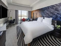 Novotel Makkah Thakher City modern hotel room with white bed, striped rug, sofa and abstract blue wall