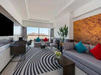Novotel Makkah Thakher City modern hotel suite with grey sofas, colourful cushions, wood wall and striped rug