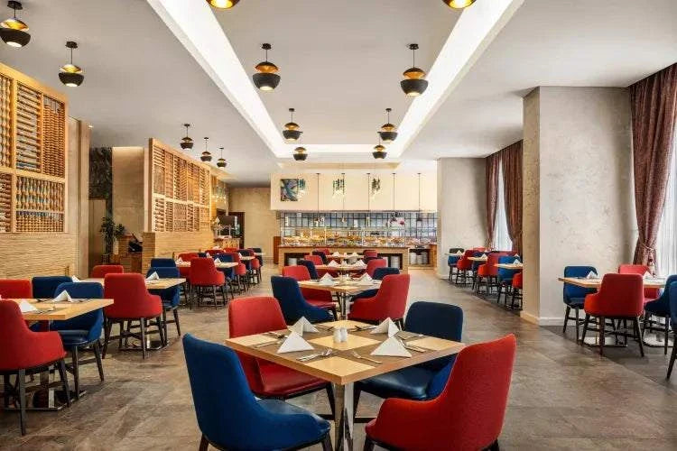 Novotel Makkah Thakher City restaurant with modern dining area, red and blue upholstered chairs, and set tables