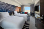 Novotel Makkah Thakher City twin hotel room with white beds, colourful cushions, wall art, TV and mountain view