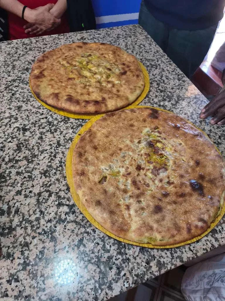 Berber style stuffed pizza with golden brown crust on yellow plates, shown ready to Order Pizza at Restaurant Nora