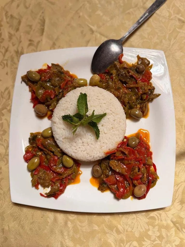 Berber pizza plate with red pepper, olives, and herbs surrounding a circular rice mound garnished with mint, perfect to Order Pizza.