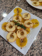 Plate of sliced apple rings and orange slices sprinkled with brown spice and garnished with fresh green mint leaves perfect to Order Pizza dessert accompaniment