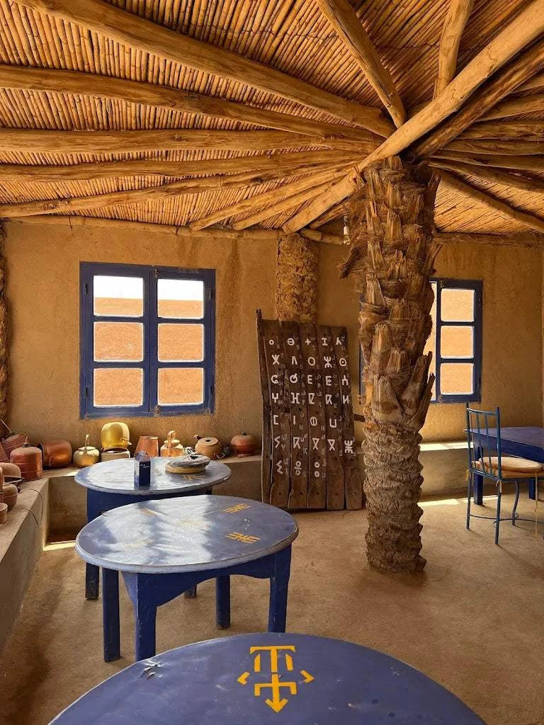 Order Pizza at restaurant seating with blue round tables, wooden roof beams, and beige clay walls featuring traditional decor.
