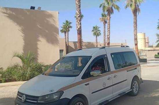 White Volkswagen van with brown stripes parked outside near palm trees, suitable for Private Taxi Rent in Morocco