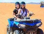 quad bike ride featuring two riders on a blue all-terrain vehicle with helmets, set on golden desert dunes