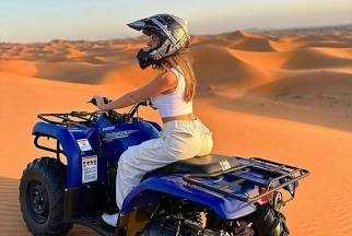 quad bike ride featuring a blue quad bike with a rider wearing a helmet and white clothing on golden desert dunes