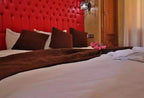 Residence Touristique Merzouga double bed with tufted red headboard, white sheets, brown pillows and blanket, and pink flowers