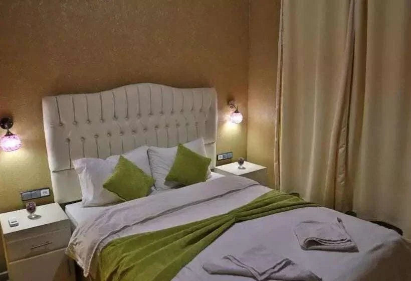Residence Touristique Merzouga bedroom with beige walls, white tufted headboard, white bedding, and green accent pillows and throw