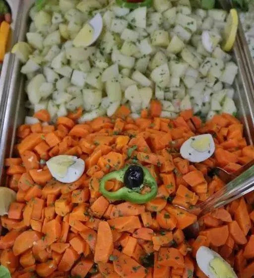 Residence Touristique Merzouga style mixed vegetable salad with diced carrots, potatoes, green pepper, olives, and boiled egg slices in a stainless steel tray