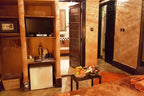 Riad Africa Marrakech cozy room with warm earthy tones, wooden doors, small fridge, TV, safe, and a table with fresh fruit basket