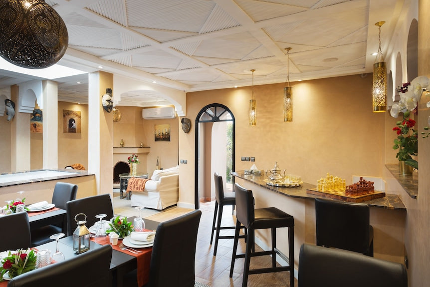 Riad Africa Marrakech dining area with beige walls, black chairs, marble countertops, and Moroccan decorative lanterns