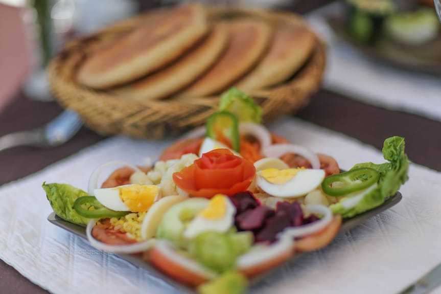 Riad Africa Marrakech plate with fresh mixed salad including lettuce, tomato, sliced boiled eggs, onion rings, and a tomato rose garnish