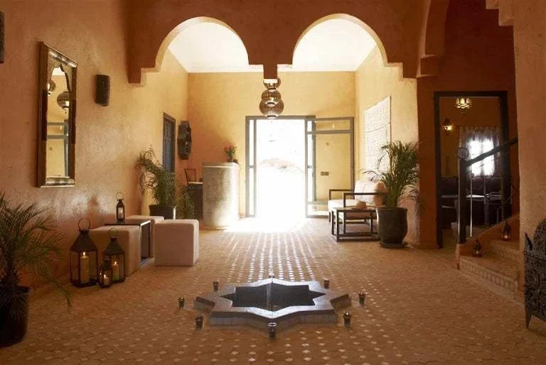 Riad Bouchedor in Ouarzazate traditional Moroccan interior with beige walls, arched ceiling, tiled floor, and central star-shaped fountain