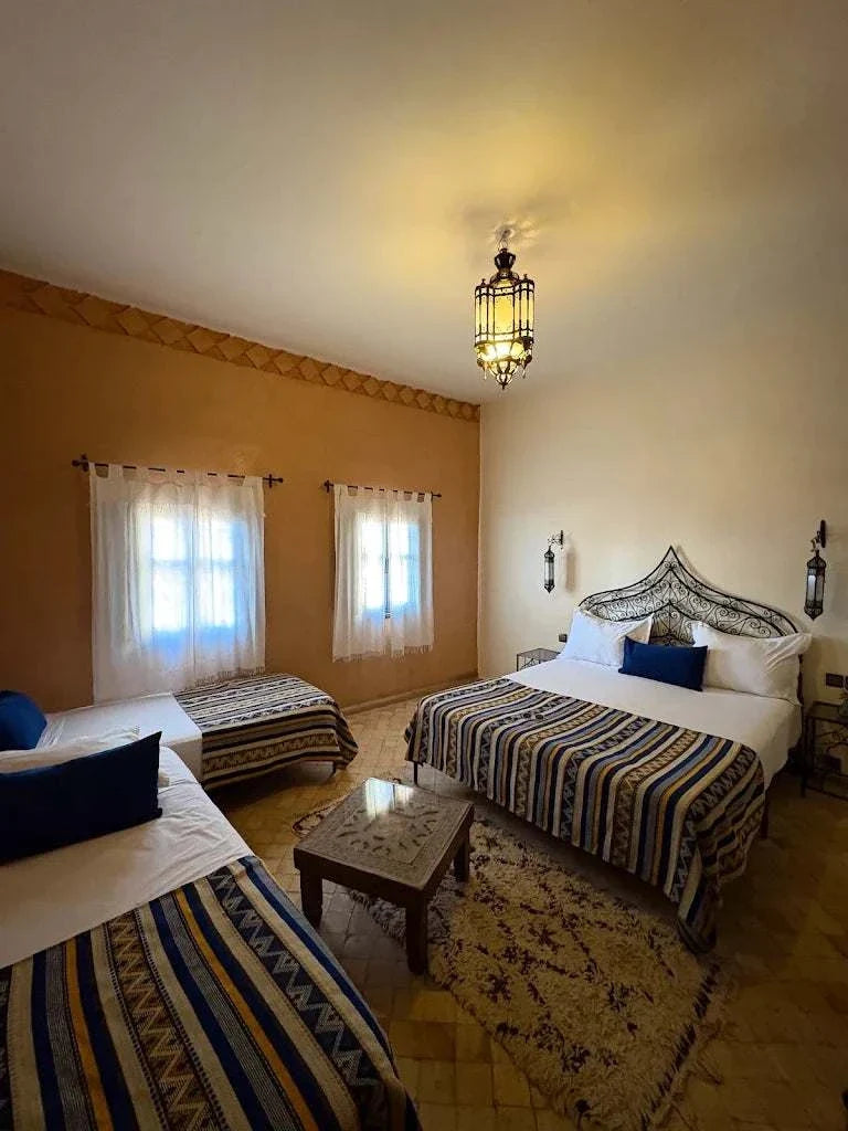Traditional bedroom in Riad Bouchedor in Ouarzazate featuring patterned textiles in blue and beige with Moroccan decor accents