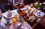 Riad Chay Boutique breakfast table with fresh bread, orange juice, eggs, and white napkins on a white tablecloth