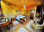 Riad Chay Boutique cozy bedroom with stone walls, warm orange lighting, patterned rugs, and wooden furniture