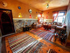 Riad Chay Boutique cozy Moroccan lounge with warm ochre walls, stone wainscoting, patterned cushions, and colorful rugs