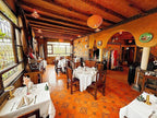 Riad Chay Boutique Moroccan dining room with warm orange tones, wooden beams, patterned tile floor, and white tablecloths