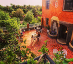 Riad Chay Boutique outdoor terrace with terracotta tile flooring, Moroccan decorative wall fountain, and guests dining at black metal tables