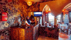 Reception area at Riad Chay Boutique featuring stone walls, carved wooden counter, warm lighting, and a smiling staff member