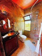 Riad Chay Boutique rustic bathroom with stone walls, copper sink, wooden vanity, white toilet, and walk-in shower