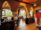 Riad Chay Boutique interior featuring warm orange tones, traditional Moroccan arches, tiled floors, and decorated dining area with tables and chairs