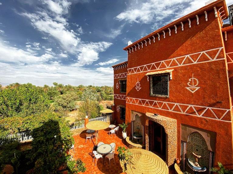 Riad Chay Boutique featuring traditional terracotta exterior walls with white geometric patterns and an outdoor seating area with tables and chairs