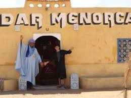 Riad Dar Menorca with two people standing at the entrance of a beige traditional Moroccan building with the name displayed above the door