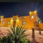 Riad Dar Menorca building in Merzouga Morocco at night with yellow-lit traditional Moroccan facade and desert plants