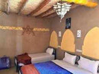 Riad Dar Menorca featuring a rustic Moroccan-style bedroom with clay walls, arched decorative niches, twin beds, and a traditional wooden ceiling