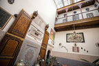 Riad Dar Tahri SPA interior courtyard with traditional Moroccan woodwork, intricate tile patterns, and ornate plaster decoration under a glass roof