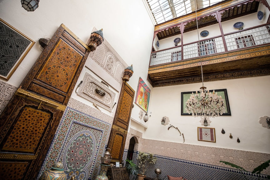 Riad Dar Tahri SPA interior courtyard with traditional Moroccan woodwork, intricate tile patterns, and ornate plaster decoration under a glass roof