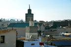 Traditional Moroccan riad buildings with beige walls and green tiled rooftops in historic Fes medina during daytime near Riad Dar Tahri SPA