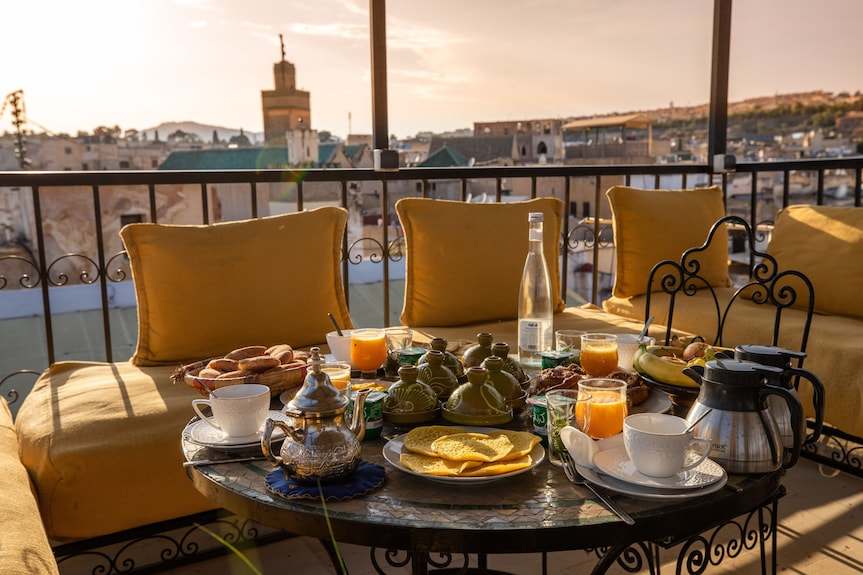Riad Dar Tahri SPA outdoor breakfast setup with yellow cushions on wrought iron seating and traditional Moroccan tea set