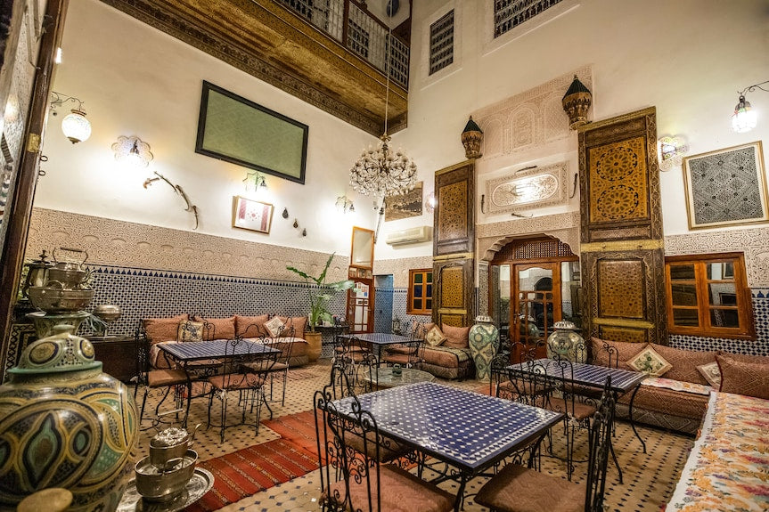 Riad Dar Tahri SPA interior with traditional Moroccan seating, decorative tiled tables, ornamental vases, and intricate woodwork